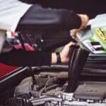 Man refilling motor oil on car engine bay
